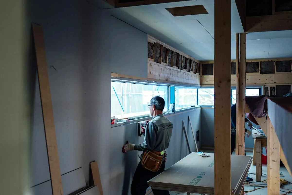 Painter finishing a repaired wall in a bright room